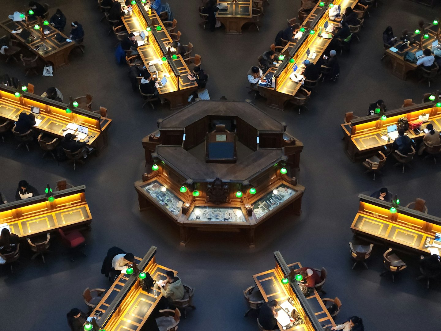 Studenti che studiano alle scrivanie in una grande biblioteca ornata.